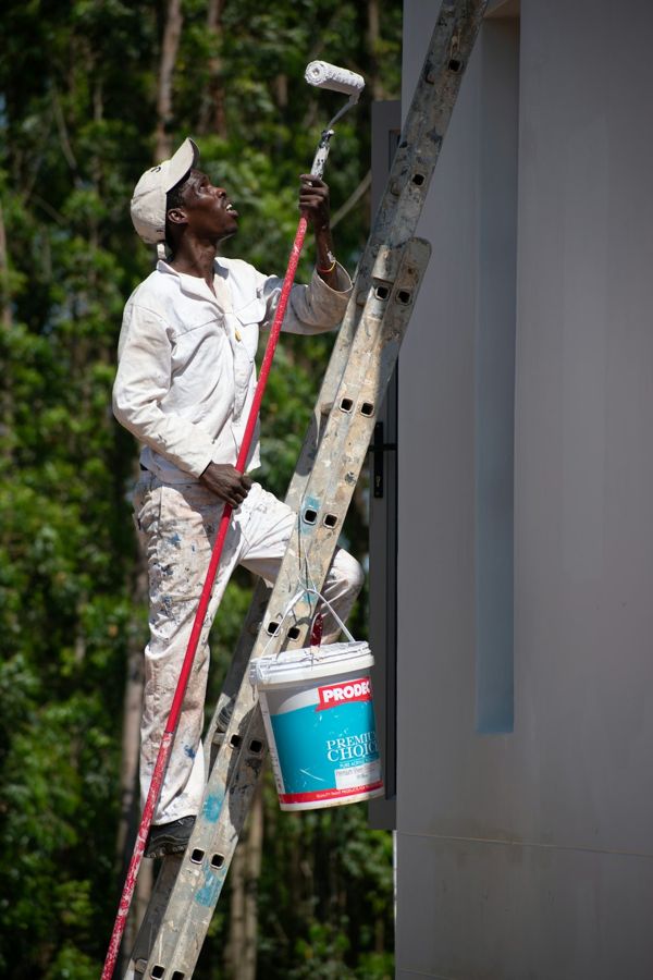 Painter on a ladder rolling paint onto a wall
